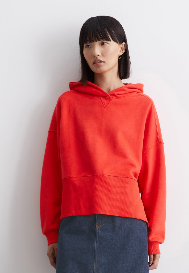 Rode hoodie met een comfortabele pasvorm, ribbelachtige boorden en lange mouwen. Gepaarde met een donkerdenim rok, met een klassieke snit.