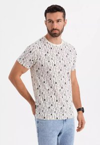 Hvid T-shirt med sort vertikal tekstmønster, rund hals, korte ærmer, lavet af bomuld, parret med lyseblå jeans.