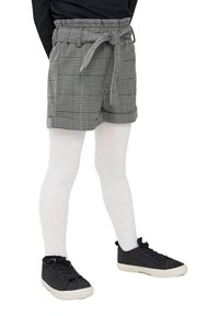 Pantaloni corti a quadri grigi con vita regolabile e risvolti, abbinati a collant bianchi e sneaker nere. Il tessuto ha una finitura testurizzata.
