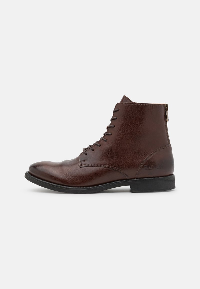 Bottine en cuir marron avec lacets et semelle noire, vue latérale montrant une fermeture éclair au talon et "Replay" embossé près de l'arrière.
