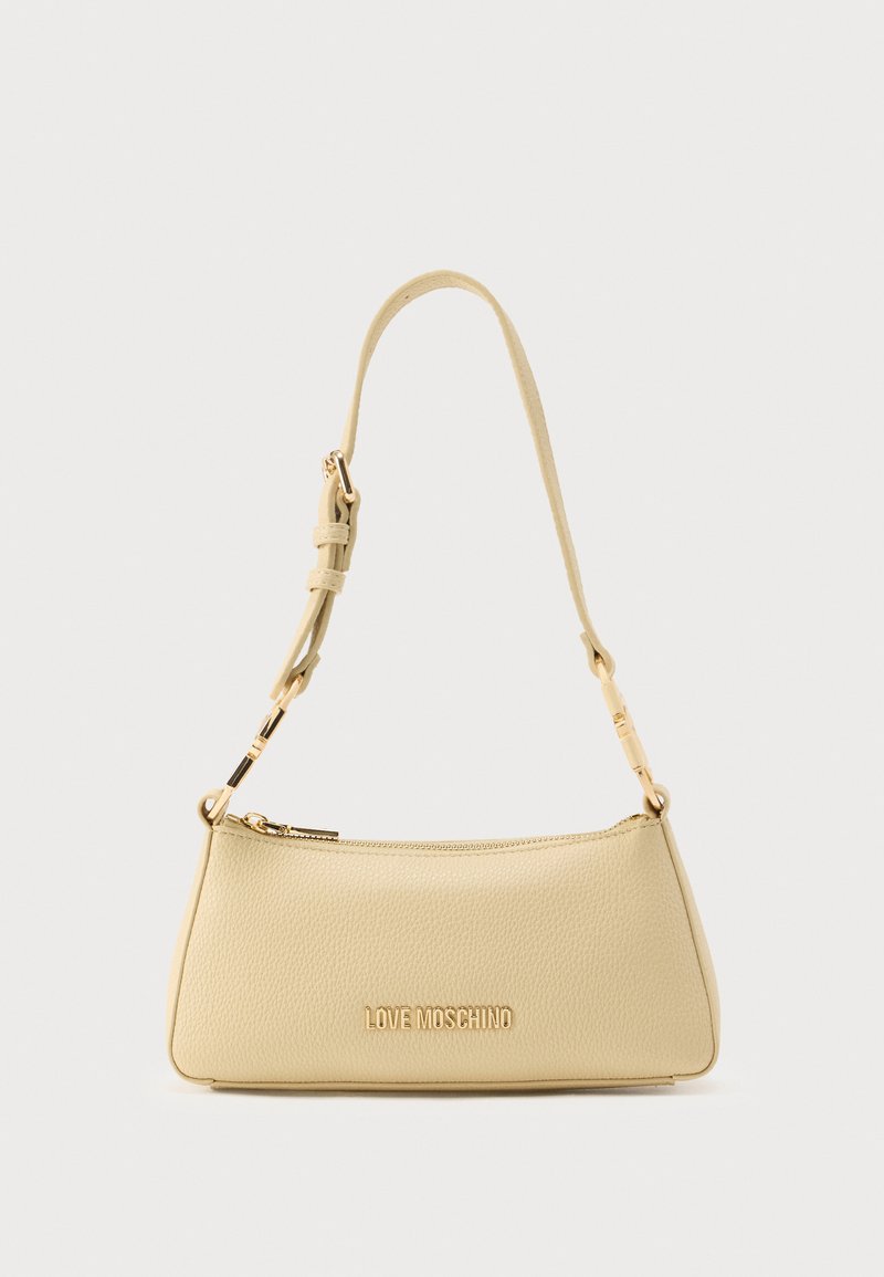 Κίτρινη τσάντα από δερμάτινη υφή με χρυσό λογότυπο, λεπτό ρυθμιζόμενο ιμάντα και φερμουάρ. Σχεδιασμός σε στυλ τσαντάκι με γωνιακό σχήμα.