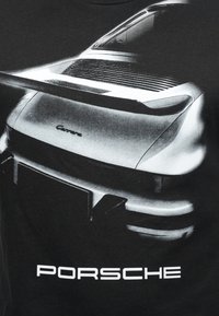 Μαύρο μπλουζάκι με μεγάλο, λεπτομερές γραφικό ενός Porsche 911 Carrera σε μονόχρωμο, με χαρακτηριστικές καμπύλε ς και κομψά σχεδιαστικά στοιχεία.