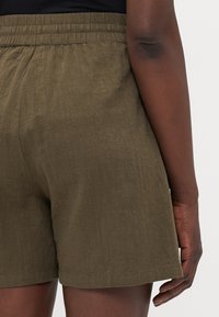 Olive green shorts with a textured fabric, featuring an elastic waistband and a simple hem finish. View shows back of shorts.