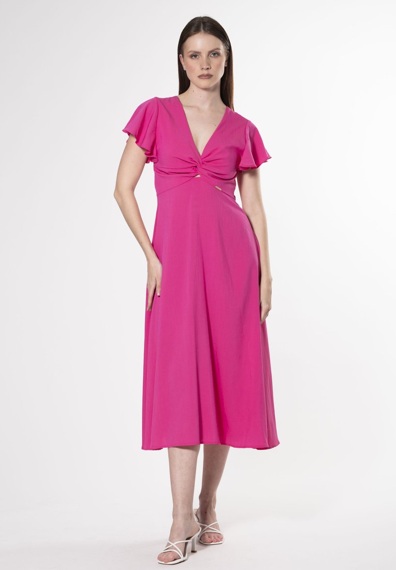 Fuchsia midi-kjole med korte flæseærmer, dyb V-udskæring, tvistet knude detalje ved taljen, og blødt stof der falder til en udvidet kant.