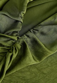 Maslinasto zelena, meka tkanina s suptilnim sjajem; sakupljena tekstura i glatki dijelovi prikazuju drapirani dizajn i skrivene dijelove.