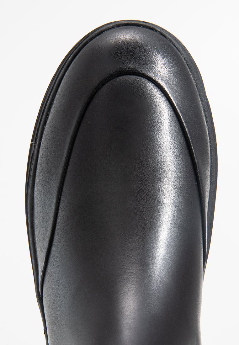 Botte de cheville en cuir noir avec une finition lisse, bout rond et détail de couture subtil le long du bord. Conçue pour le confort et la facilité d'utilisation.