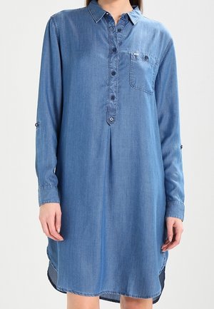 Jeanshemdkleid mit langen Ärmeln, Brusttasche, durchgehender Knopfleiste und abgerundetem Saum. Es hat eine hellblaue Farbe und eine weiche Textur.