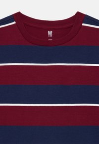 T-shirt en coton avec des rayures horizontales bordeaux et bleu marine, agrémenté de rayures d'accent blanches. Encolure ronde avec une texture douce. Étiquette de la marque visible.