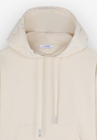 Beige hoodie met een grote, zachte capuchon, geribde mouw- en zoomafwerking, koordjes met metalen accenten en een voorzak. Merkenlabel zichtbaar aan de binnenkant.