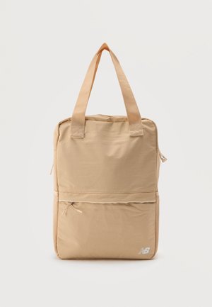 Beige rectangular tote bag with dual handles, front zip pocket, and small white New Balance logo at bottom right corner.