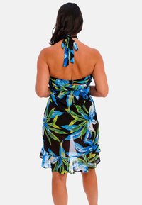 Vestido negro con grandes patrones florales en azul y verde, cuello halter con cintas, dobladillo con volantes, tela ligera.
