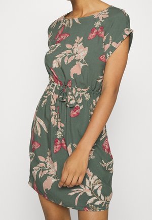 Tummaanvihreä kukkakuvioinen mekko, jossa on vaaleanpunaiset kukka- ja perhoskuviot. Mekossa on lyhyet hihat, pyöreä pääntie ja vyötärön solmittava nauha.