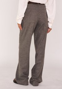 Pantaloni grigi a righe sottili con un design a gamba ampia, realizzati in un tessuto testurizzato, dotati di una vita alta e di pieghe sottili sul retro.