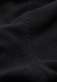 Czarna dziana tkanina o miękkiej teksturze, subtelnej rybce i szczegółowych wzorach szycia. Zbliżenie podkreśla spójność splotu.