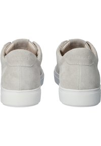 Baskets en daim beige avec semelles blanches, vues de dos, montrant des collerettes de talon rembourrées et des détails de coutures subtiles.