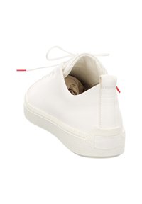 Witte leren sneaker met een gestructureerde witte rubberen zool, platte veters en een achtertab met een rode accent. Minimalistisch ontwerp met strakke lijnen.
