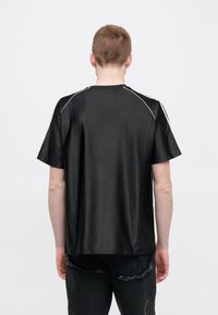 Μαύρο T-shirt με κοντά μανίκια κατασκευασμένο από γυαλιστερό υλικό, με λευκή ραφή στους ώμους. Σχεδίαση με ίσια γραμμή και άνετη εφαρμογή.