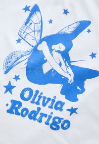 T-shirt blanc avec un motif graphique bleu représentant une silhouette aux ailes de papillon et des étoiles, accompagnée du texte "Olivia Rodrigo".