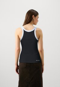 Svart ribbad linne med ljusgrå kant; den figurnära designen framhäver ryggen; tyget ser slätt och elastiskt ut. Märke längst ner.