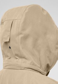 Giacca con cappuccio beige dal design elegante. Presenta una texture liscia, cuciture visibili e un dettaglio di bottone scuro sulla spalla.