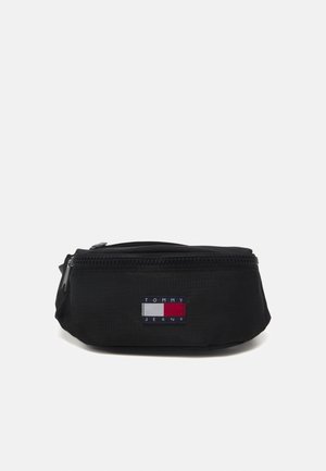 Black Tommy Jeans waist bag with front zipper and rectangular logo patch in white, red, and navy colors.