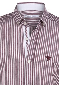 Camisa de rayas verticales marrón y blanca con cuello abotonado, logo de pájaro bordado y tejido texturizado.