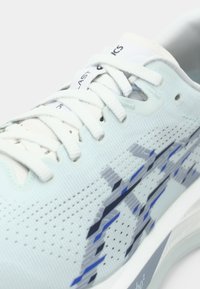 Chaussure de course bleu clair avec tige en mesh, lacets blancs et surface texturée avec des accents bleus et navy. Conçue pour la respirabilité et le confort.