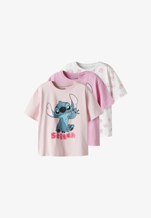 Tre børne-T-shirts i pink og hvid; forreste skjorte viser figuren Stitch med teksten "Stitch" i pink bogstaver.