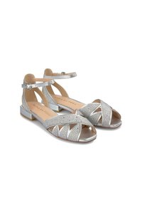 Zilveren sandalen met enkelbandjes kenmerken zich door contrasterende texturen, versierd met studs, een open te ontwerp en een lage blokhak.