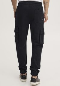 Zwarte katoenen cargo pants met zijzakken, een elastische tailleband en boorden. Kenmerkt zich door een gladde textuur en een eenvoudig ontwerp.