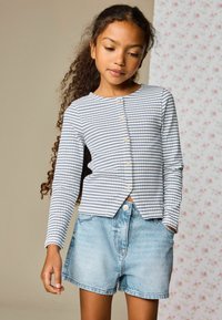 Top de manga larga de algodón a rayas en azul claro y azul marino, con cuello redondo y cierre de botones, combinado con shorts de mezclilla.