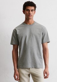 Jasnoszary, krótki rękaw, bawełniany T-shirt. Posiada okrągły dekolt, luźny krój i gładką fakturę. Brak widocznych wzorów lub akcentów.