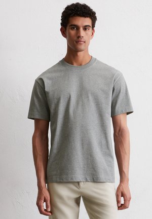 Lichtgrijze T-shirt met korte mouwen van katoen. Heeft een ronde hals, een losse pasvorm en een gladde textuur. Geen zichtbare patronen of accenten.