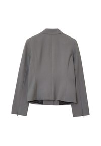 Giacca grigia su misura con colletto a revers, maniche lunghe e retro corto. Presenta una superficie liscia e una chiusura con zip alla base.