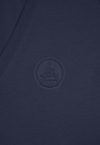 Camiseta de cuello en V de color azul marino, confeccionada con una tela suave que presenta un logo en relieve en el pecho. La textura es suave con detalles sutiles de costura.
