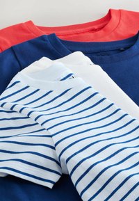 Stabel af foldede bomulds T-shirts i koralrød, marineblå, ensfarvet hvid og hvid med blå vandrette striber.
