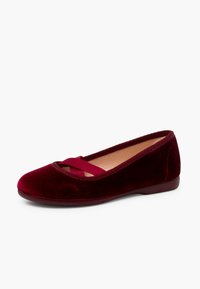 Ballerine in velluto bordeaux con punta arrotondata, dettagli con cinturino incrociato e suola piatta flessibile. La texture liscia enfatizza il design complessivo.