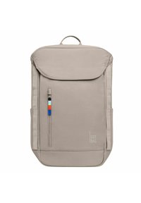 Sac à dos beige avec une surface texturée, rabat supérieur, poche zippée à l'avant et un tirant de fermeture éclair coloré. Le logo est imprimé sur le côté.