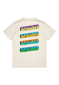 Krémové bavlněné tričko s barevným, výrazným logem "DCSHOES" v purpurové, žluté, oranžové, modré a zelené barvě, umístěným vertikálně na zadní straně.