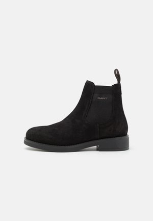 Botte Chelsea en daim noir avec panneau latéral élastique, languette de tirage, talon bas et logo de la marque sur le côté, vue de l'extérieur.
