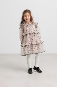 Heled roosa täpikleid, millel on rüüsid ja must äär. Kihtide disain, kaasas valged sukkpüksid ja mustad kingad. Sile kangas.