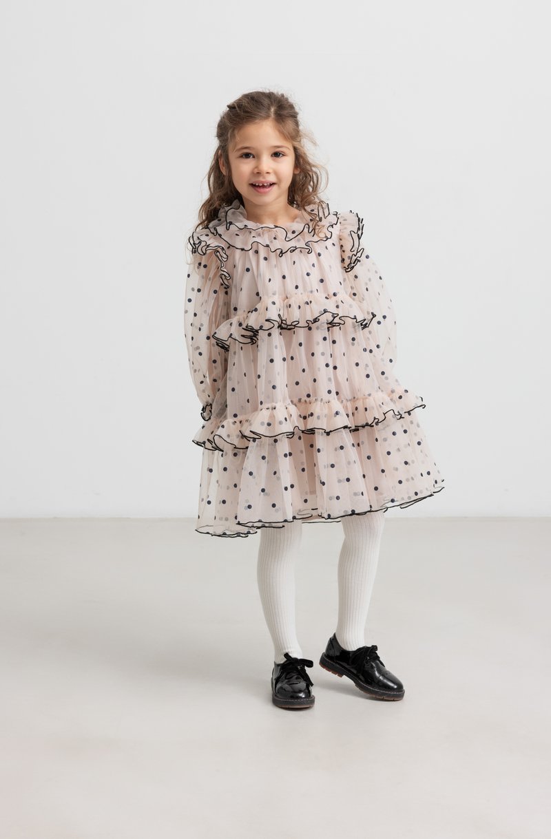 Heled roosa täpikleid, millel on rüüsid ja must äär. Kihtide disain, kaasas valged sukkpüksid ja mustad kingad. Sile kangas.