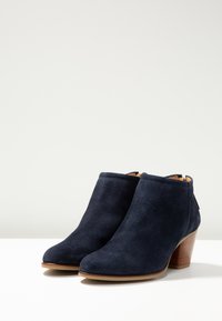 Stivaletti alla caviglia in camoscio blu navy con punta arrotondata, tacco medio impilato e texture liscia. Dettaglio con zip sul retro.