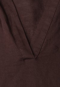 Tissu marron foncé avec un décolleté en V et des détails de couture visibles en gros plan.