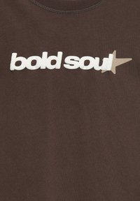 Brązowy t-shirt z białym napisem "bold soul" i beżowym akcentem w kształcie gwiazdy. Wykonany z miękkiego materiału, z okrągłym dekoltem.