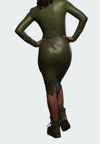 Figurbetontes, olivgrünes Fake-Lederkleid mit langen Ärmeln und einem Schlitz im Rücken, kombiniert mit dunkelgrünen Schnürstiefeln.