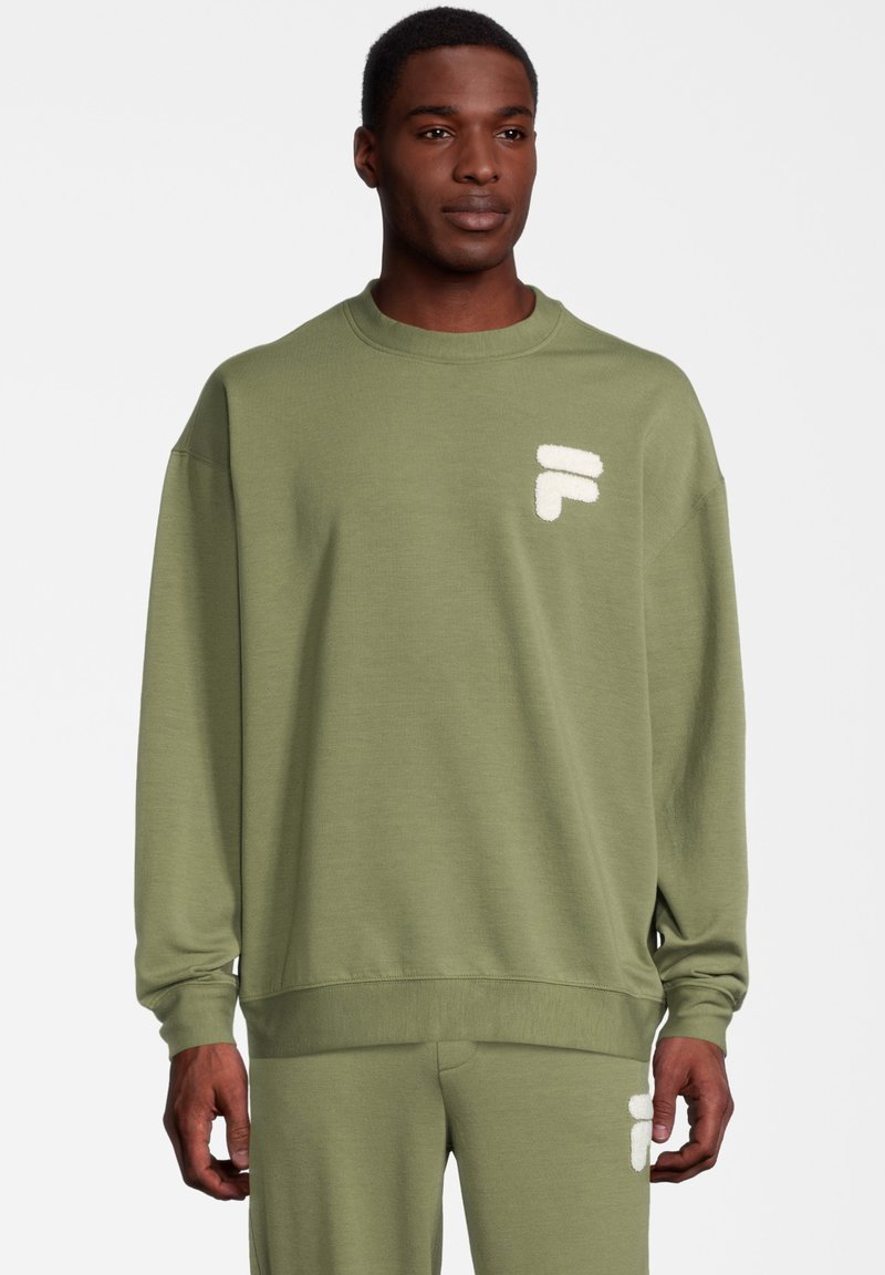 Sudadera verde oliva con cuello redondo y mangas largas. Presenta un logo blanco de peluche en el pecho. Tejido suave y corte relajado.