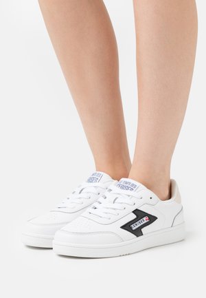 Witte sneakers met een gladleren bovenwerk, zwarte accenten, een gestructureerde rubberen zool en een logo aan de zijkant. Vetersluiting met ronde neus.