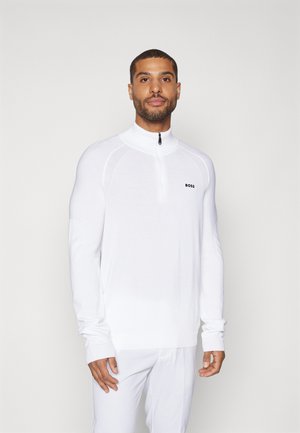 Pullover bianco a maniche lunghe con colletto a zip a un quarto, pannellature testurizzate sulle spalle e un piccolo logo nero sul lato sinistro del petto.