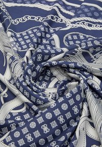 Tissu à motif marine avec des designs géométriques blancs, des chaînes et des motifs. Texture lisse avec des plis drapés. Convient à diverses utilisations.